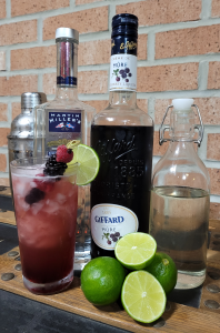 Photo of ingredients for making a Bramble cocktail: Gin, blackberry liqueur, simple syrup, fresh limes. 