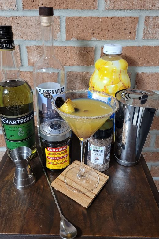 Image of the un-named cocktail devised for this episode. Ingredients include green Chartreuse, PlayPen Vodka, pineapple juice, Luxardo Maraschino Cherries, and FrexhJax Cherrywood Smoked Sea Salt
